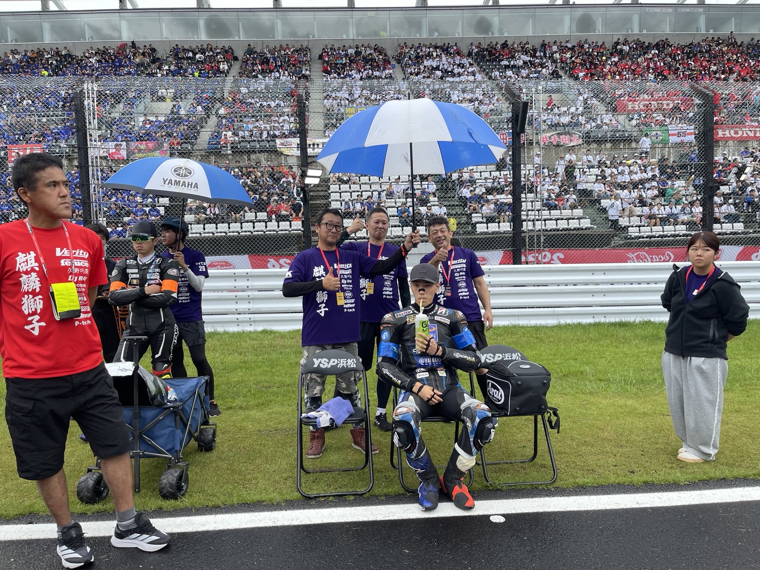 観客席を背にスタートを待つライダーとチームスタッフ